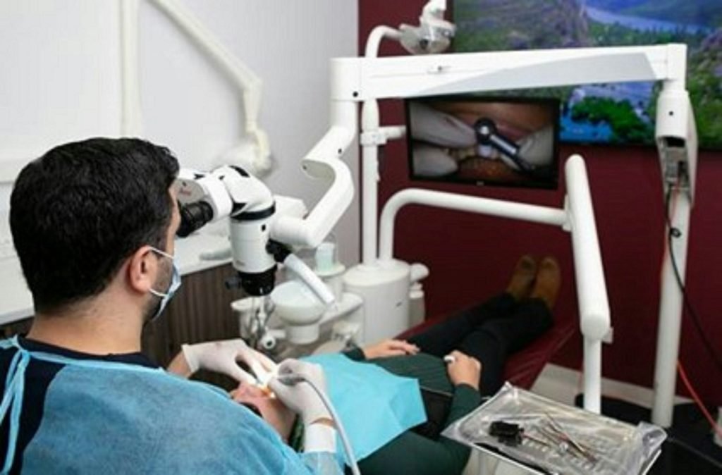 A dentist working under a microscope during treatment